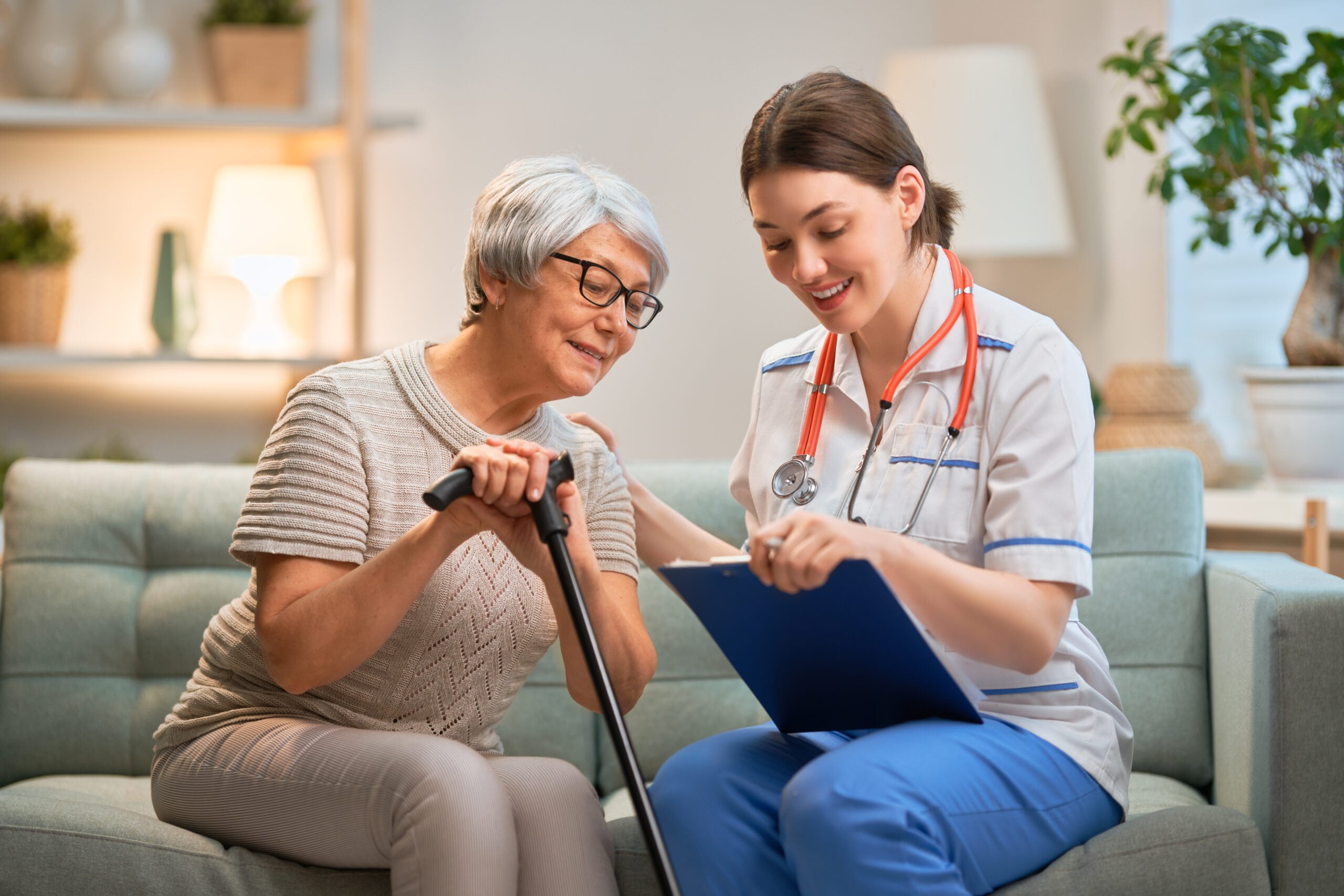 Happy patient and caregiver spending time together. Senior woman holding cane.